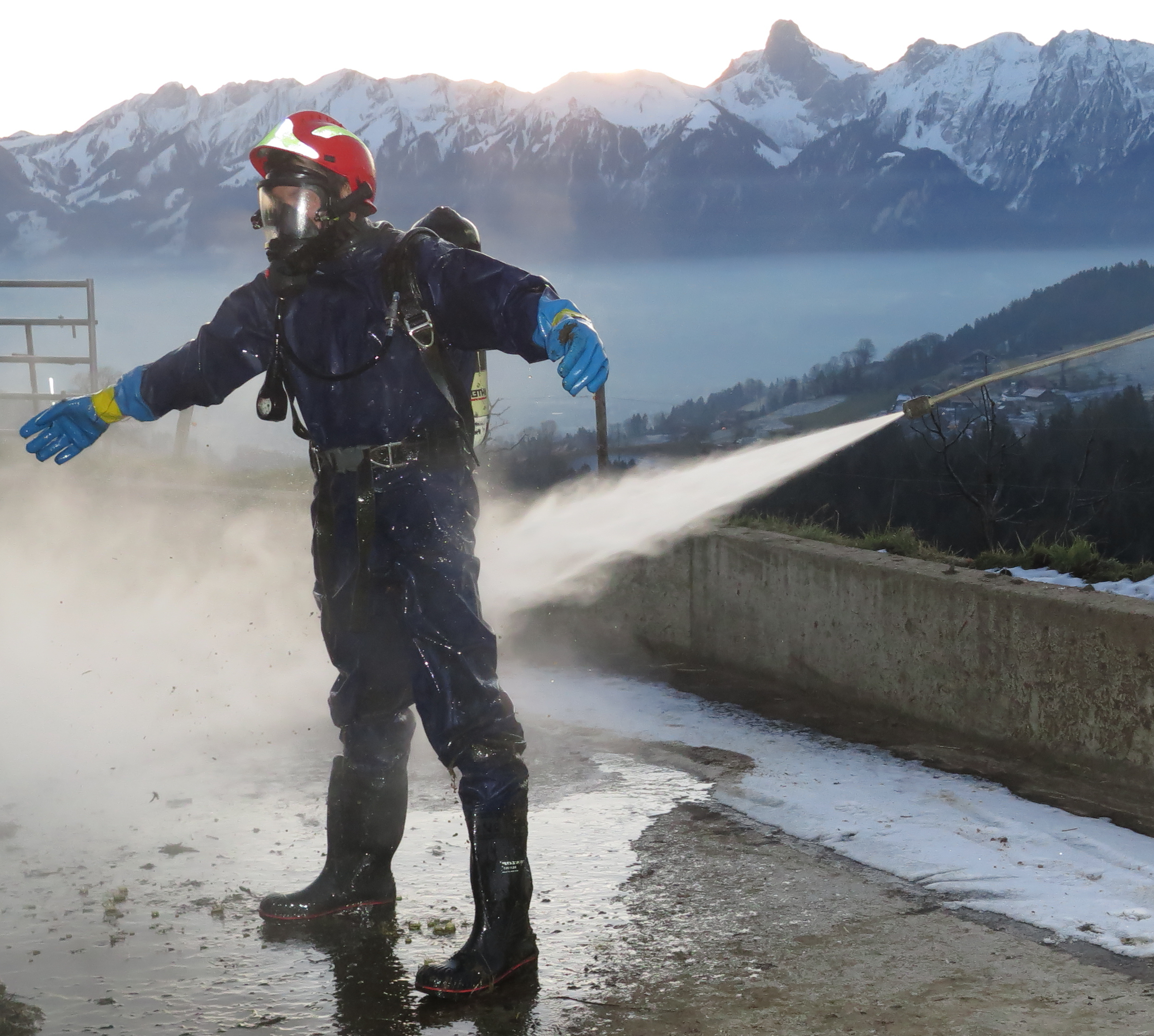 Trockenschutzanzug Pegasus 13 Feuerwehrmann in Schutzausrüstung mit Atemschutz wird bei Tierrettungseinsatz mit Hochdruckstrahl dekontaminiert.